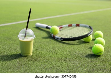 Green smoothie and tennis racket and balls on the court - Powered by Shutterstock