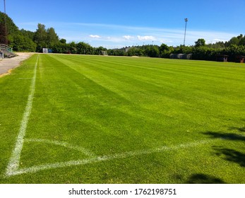 Green soccer field in June, 2020.  Natural soccer grass, outdoor. The corner with white stripes. Football is a very popular sport. Stockholm, Sweden.