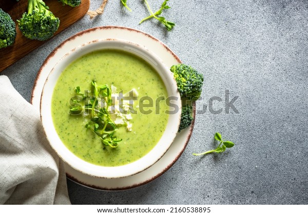 Green soup. Broccoli cream\
soup with cream and parmesan. Healthy vegan dish. Top view at white\
table.