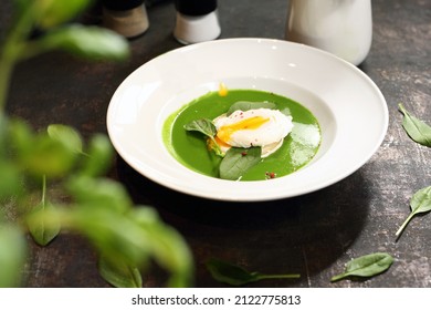 Green soup, creamy spinach soup with egg and goat cheese.
Appetizing dish on a plate, culinary photography. Food background.