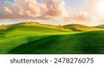 green spring hills with young grass and amazing growing fields and hills with beautiful bright cloudy sunset on background of rural landscape