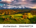 Green spring meadow with snowy mountains in the backgroound and colorful sky. High Tatras NP, Slovakia. Vysoke tatry. Osturna village