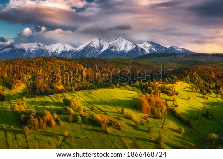 Green spring meadow with snowy mountains in the backgroound and colorful sky. High Tatras NP, Slovakia. Vysoke tatry. Osturna village Stock foto © 
