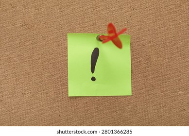 Green sticky note with exclamation mark pinned on board
