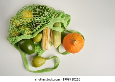 Green string eco shopping bag with vegatables avocado, corn, lemon and pumpkin on grey background. High quality photo