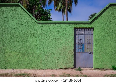 Green Stucco Wall With An Iron Door In A Tropical Beach Town In Mexico.