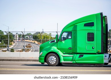 Green Stylish Bonnet Big Rig Semi Truck Tractor With Sleeping Cab Compartment For Truck Driver Rest Transporting Cargo In Black Covered Semi Trailer Running On The City Street Bridge