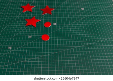 A green surface with a red star and three red stars on it. The stars are placed in a row and are surrounded by a green background - Powered by Shutterstock