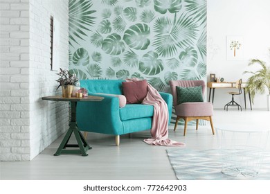 Green Table With Plant Next To Blue Sofa And Pink Armchair With Pillow Against Green Wallpaper In Living Room