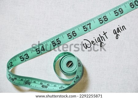 Green tape measure with the inscription weight gain on textured background.