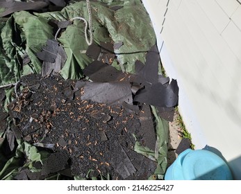 A Green Tarp Covering A Garden Area With A Bunch Of Old Shingles Lying On It.