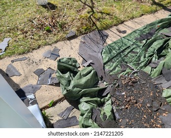 A Green Tarp Covering A Garden Area With A Bunch Of Old Shingles Lying On It.