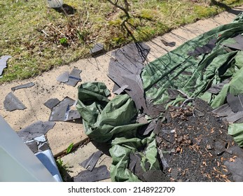 A Green Tarp Covering A Garden Area With A Bunch Of Old Shingles Lying On It.