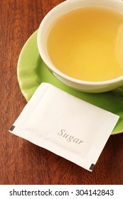 A green tea cup with sugarpacket  on the wooden table    