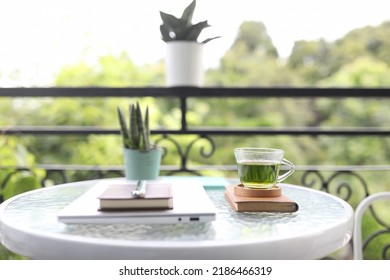 Green Tea Glass Cup And Folded Laptop And Notebooks On Glass Table Balcony Outdoor