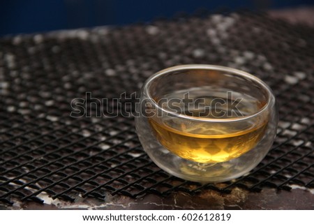 Green tea in a glass transparent bowl. Small cup of tea on table of stone. Glass piala with double walls, double-bottomed bowl. Meal, aperitif, repast.