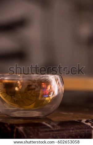 Green tea in a glass transparent bowl. Small cup of tea on table of stone. Glass piala with double walls, double-bottomed bowl. Meal, aperitif, repast. Blurred background