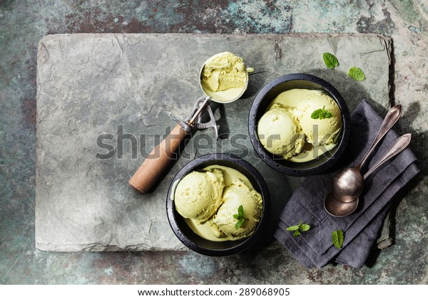 Green tea ice cream with mint leaves and\
Spoon for ice cream on stone slate\
background