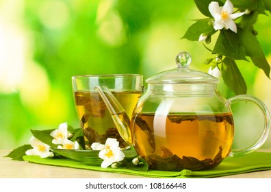 green tea with jasmine in cup and teapot on wooden table on green background - Powered by Shutterstock