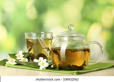 green tea with jasmine in cup and teapot on wooden table on green background - Powered by Shutterstock