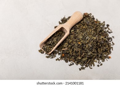 Green tea on a gray texture background. Dry green tea leaves. Fragrant tonic drink. Side view. Place to copy.