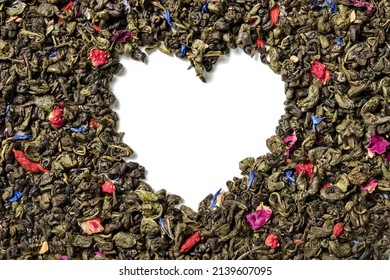 Green tea with strawberry, goji berries, knapweed petals and rose buds on white background. Heart shaped. Top view. Close up. High resolution.