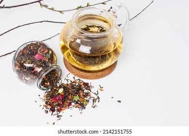 Green tea in a teapot on a white table. Loose leaf tea in a transparent glass jar. Advertising for the sale of tea. Hot herbal tea