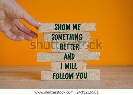 Green text Show me something better and i will follow you on brick blocks. Beautiful orange background, wooden table, copy space. Businessman hand. Business concept. Stock photo © 