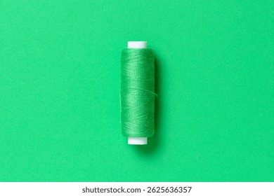 Green thread spool close-up flat lay top view with copy space for text