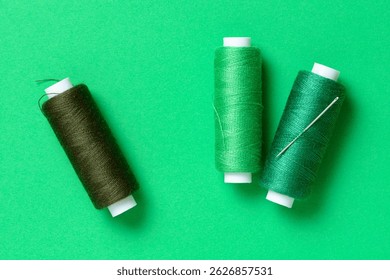 Green thread spools with needle background with copy space for text close-up flat lay top view
