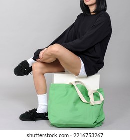 Green Totebag With Model Wearing Black T Shirt Long Sleeve And White Shorts