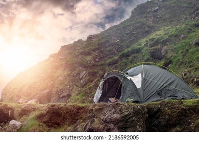 Green Tourist Tent In A Rough Mountain Area. Cool Morning Mood. Camping Area. Outdoor Holiday In A Nature Area. Sun Flare Over Mountain Ridge.