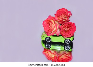 Green Toy Car With A Large Bouquet Of Flowers On A Neon Mirror Background. Congratulations On Your Birthday, Holiday, Valentine's Day, Merry Christmas, Flower Delivery For Sale, Selective Focus,