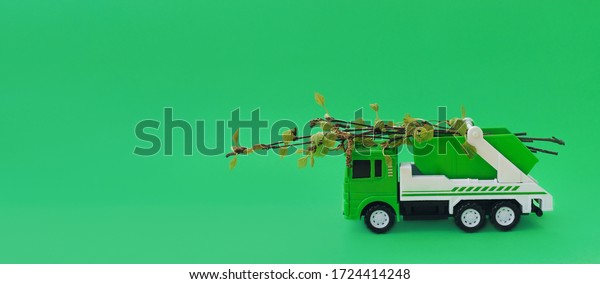 Green toy garbage\
truck carries fresh branches of trees with leaves.Concept of waste\
recycling,zero waste.Concept of caring for the environment.Copy\
space for text