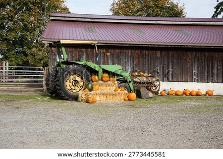 Green Tractor Surrounded by Pumpkins and Hay Bales on a Farm”