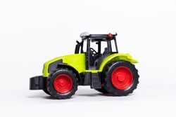 A Green Tractor Toy Car On A White Background.it's Small And Cute. 