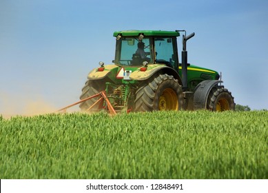 Green Tractor Working In The Field.