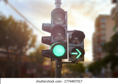 Luz verde de tráfico con flecha verde iluminada en la ciudad mientras el atardecer permite al auto girar a la derecha