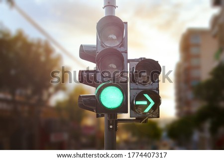 Green traffic light with green arrow light up in city while sunset allows car to turn right