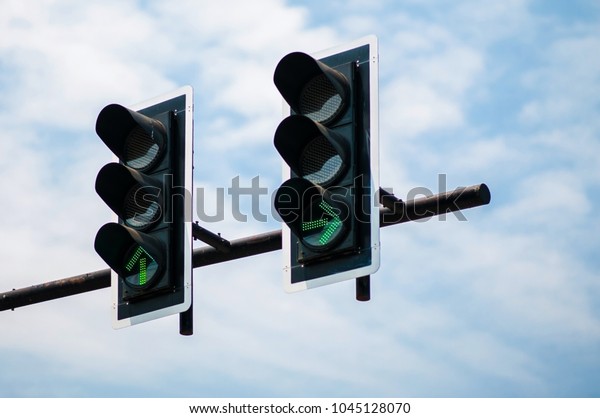Green traffic light green direction light\
against soft blue sky\
background