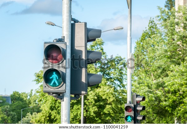 Green traffic light signal for pedestrians on the\
crosswalk in the city