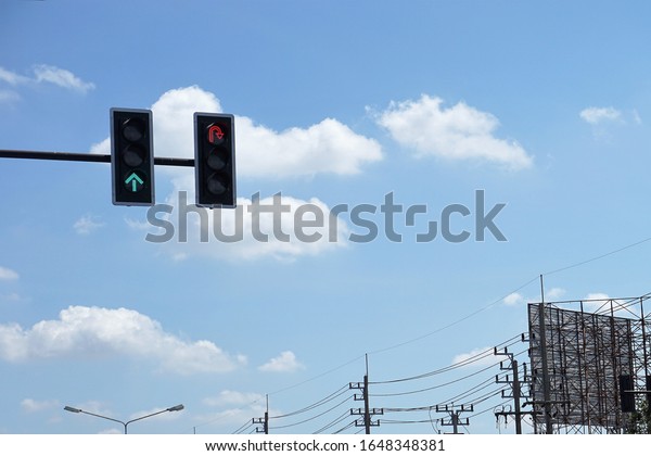Green traffic lights go straight and symbolic\
stoplight red traffic lights wait for U-turn. On a beautiful white\
clouds and blue sky in\
background.