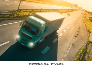 Green truck in motion blur on the highway at sunset