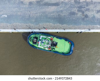 Green tugboat docked on the river Scheldt in Antwerp. Drone aerial top down view from above