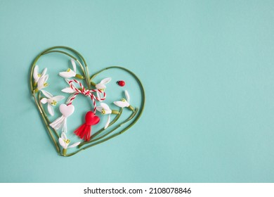 Green and turquoise background with a heart of snowdrops and red and white lace with tassels. Postcard for the holiday on March 1, Martisor, Baba Marta. - Shutterstock ID 2108078846