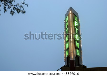 Green Uptown Neon Sign Against A Cloudy Blue Dusk Sky