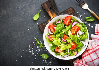 Green vegan salad from green leaves mix and vegetables. Top view on black. - Shutterstock ID 1519672568