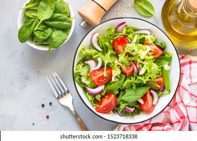 Green vegan salad from green leaves mix and vegetables. Top view on gray stone table.