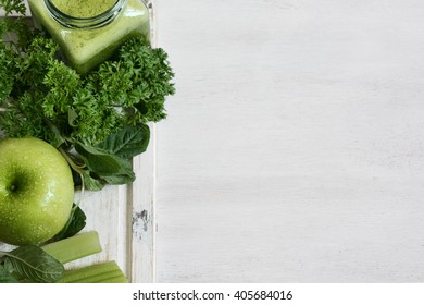 Green vegetable juice in the jar and ingredients on the white wooden background. Diet concept. Detox.