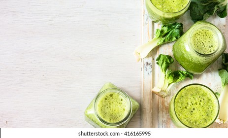 Green vegetable smoothie in jars and ingredients on the white wooden background. Diet concept with text space. Detox. Vegetarian food